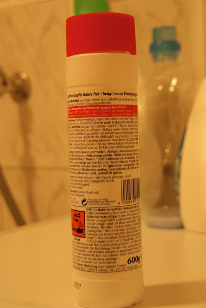 Bottle of drain cleaner standing in a bathroom sink.