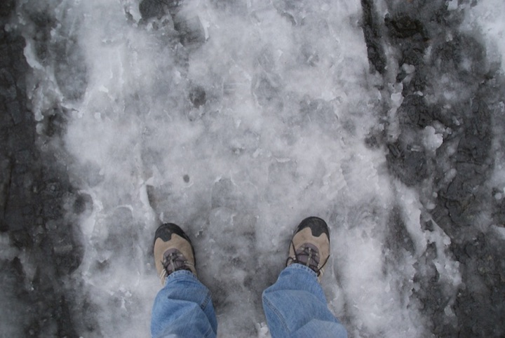 View downward at two shoes on melting ice.