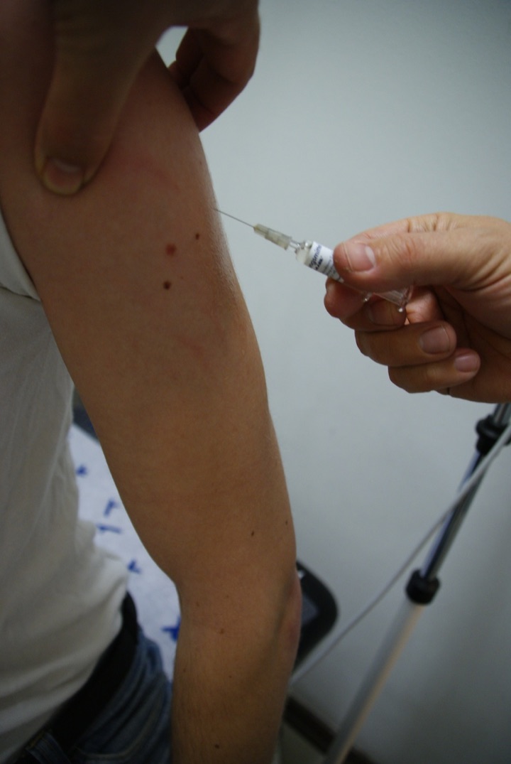 A syringe being used to inject an upper arm.
