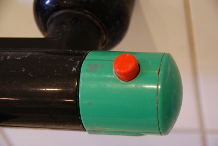 Green shower thermostat with a red safety button and a 38-degree limit.