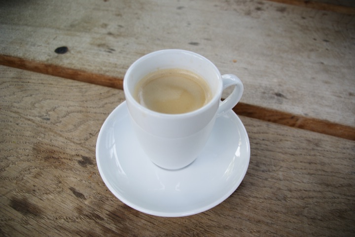 White espresso cup on a weathered tabletop.