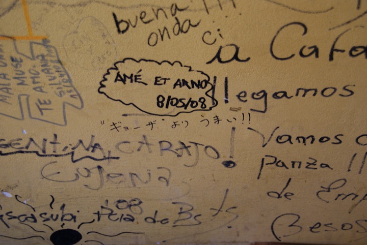 Close-up of handwritten customer comments on a restaurant wall.