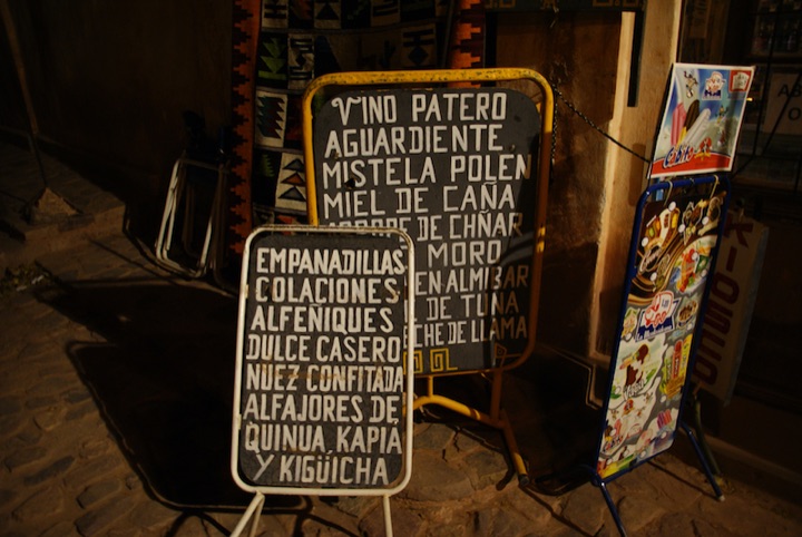 Two hand-lettered menu boards listing foods and drinks outside a shop.