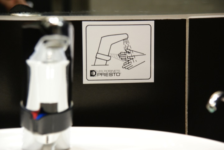 A water faucet beside a pictogram showing hands under running water.
