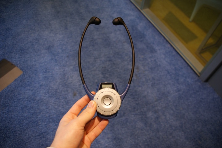 Hand holding a tour-guide earpiece device on a blue carpet.