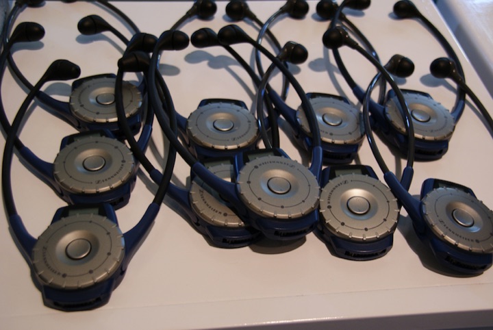 Several tour-guide earpiece devices arranged on a table.