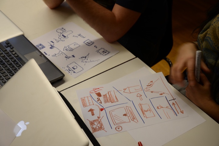 Participants drawing service concepts on paper beside laptop computers.
