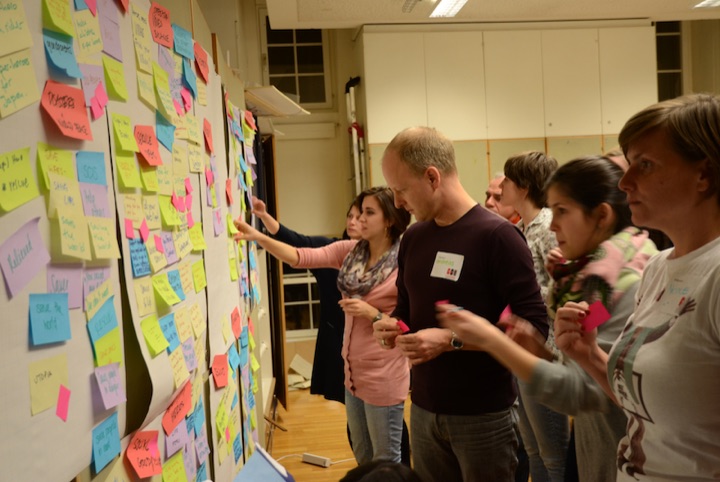 Participants adding colored sticky notes to a workshop wall.