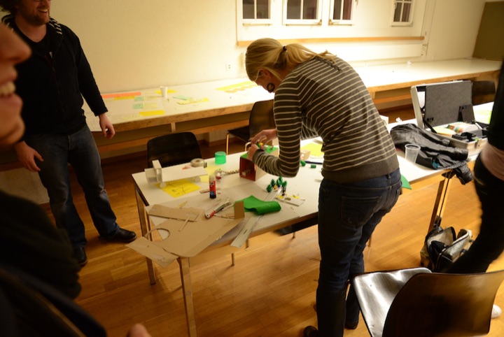 Participant building a cardboard prototype at a workshop table.