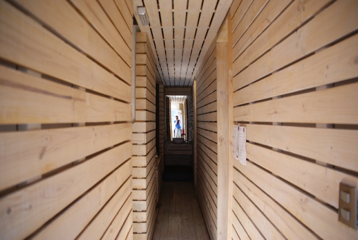 Narrow wooden corridor with a person standing at the far end.