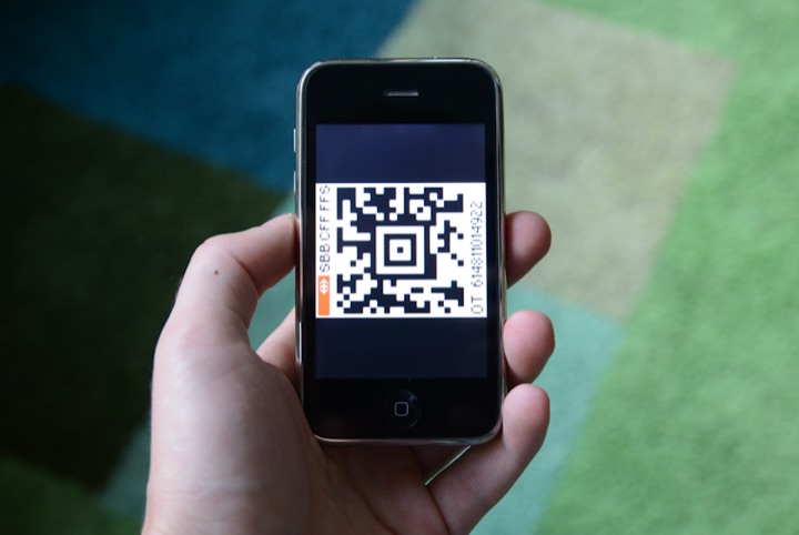 Hand holding a smartphone displaying a QR code.