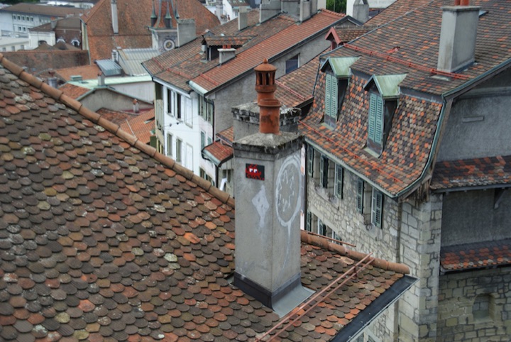 Red pixel-art ghost figure on a chimney above tiled rooftops.