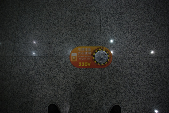 Round 220V power socket set into a dark stone floor.