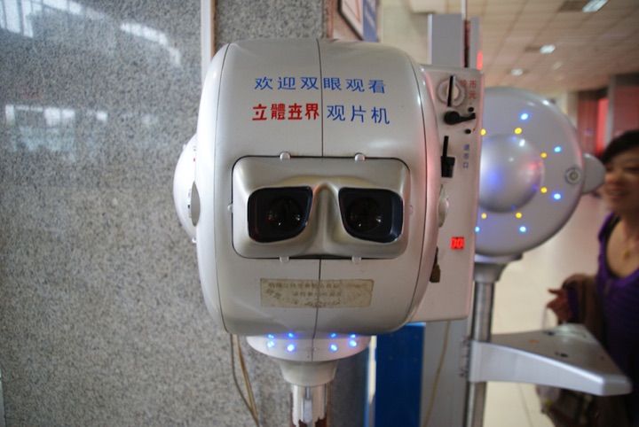 Coin-operated stereoscopic viewing machine with Chinese text and blue indicator lights.