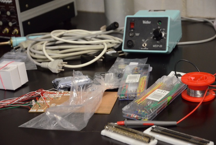 Soldering station, wire, electronic components, and tools on a workbench.