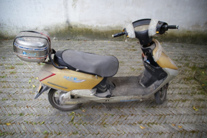Yellow scooter with its handlebars and front panel wrapped in white duct tape.