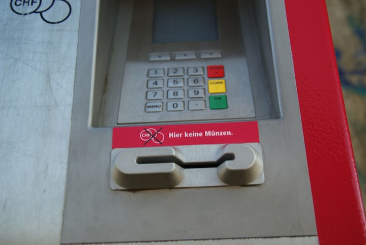 Close view of a card-payment terminal with a keypad and a German sign stating that coins are not accepted.