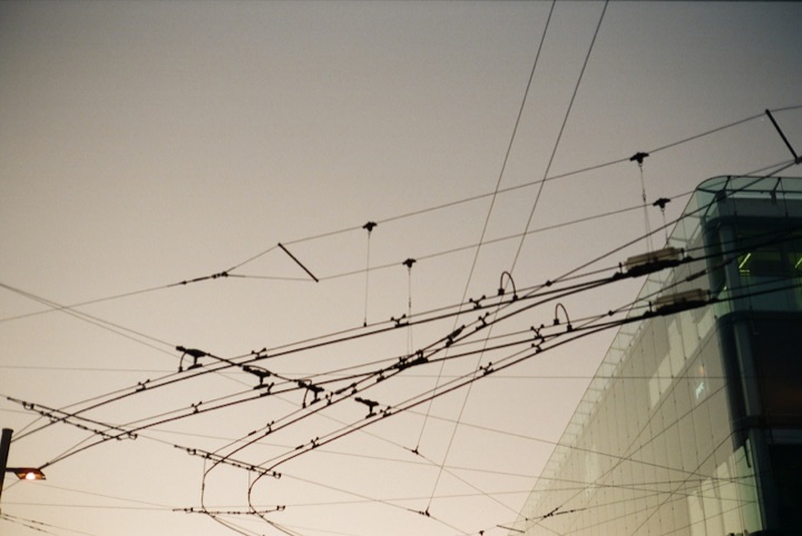 Overhead trolley wires crossing in front of a modern glass building.