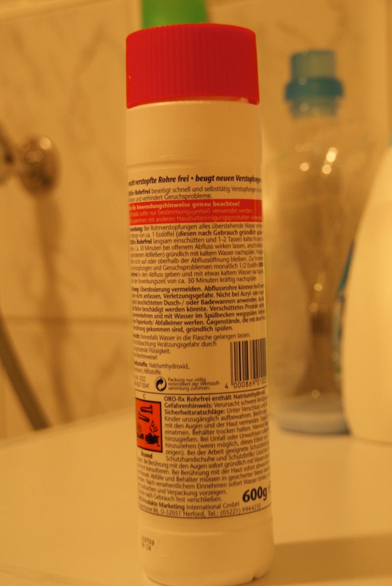 Bottle of drain cleaner standing in a bathroom sink.