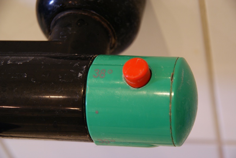 Green shower thermostat with a red safety button and a 38-degree limit.
