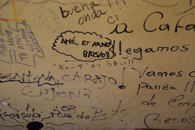 Close-up of handwritten customer comments on a restaurant wall.