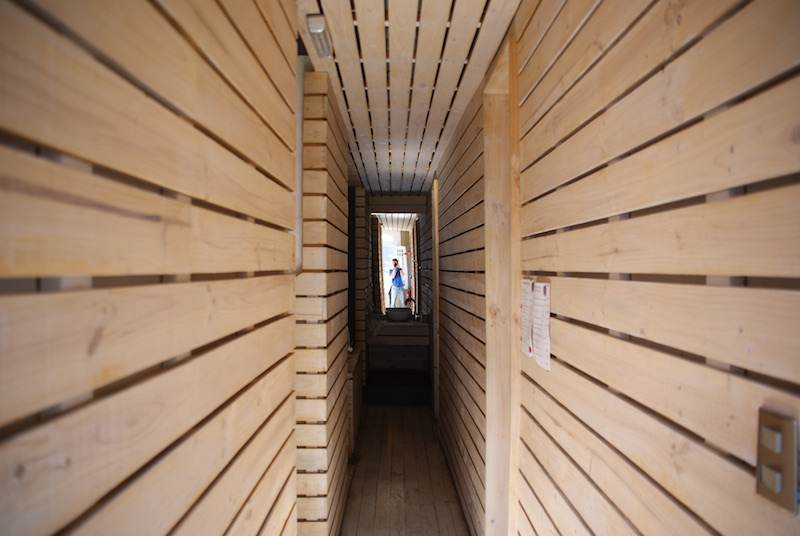 Narrow wooden corridor with a person standing at the far end.