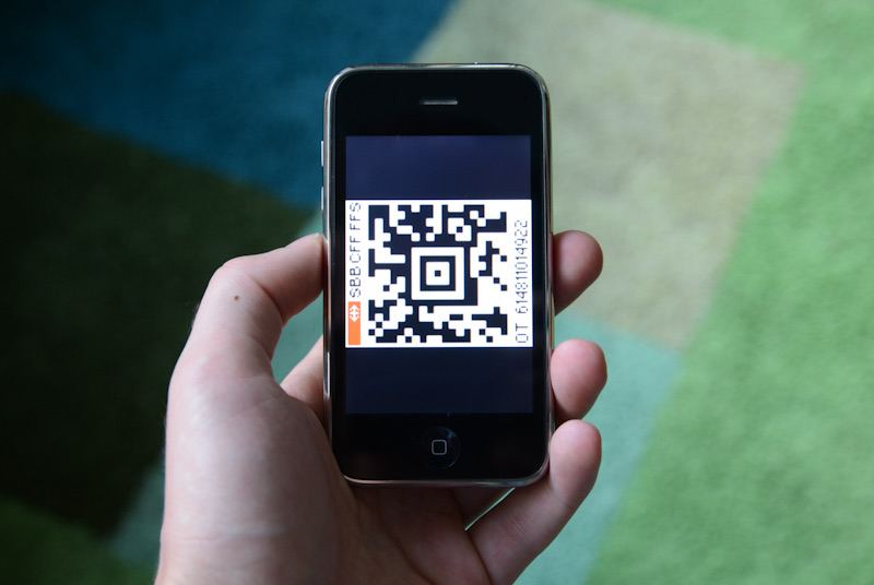 Hand holding a smartphone displaying a QR code.