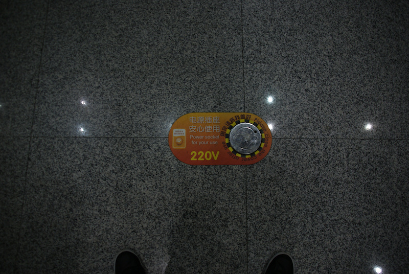 Round 220V power socket set into a dark stone floor.